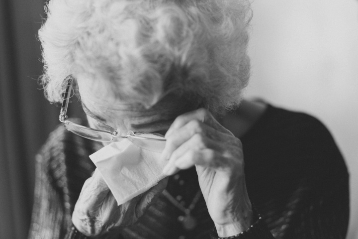 An elderly lady wiping her eyes.