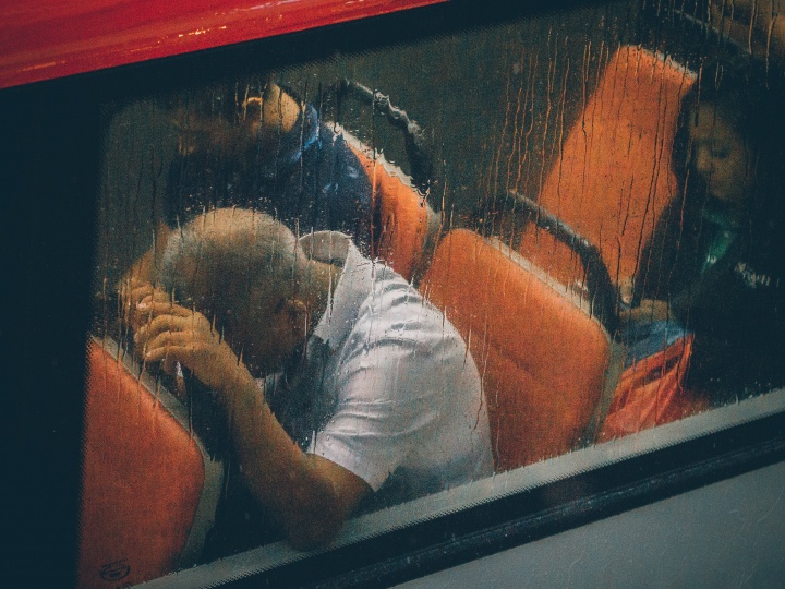 People riding a commuter train while raining. 