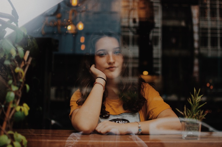 A young woman sitting with her arms on a counter looking through a window.