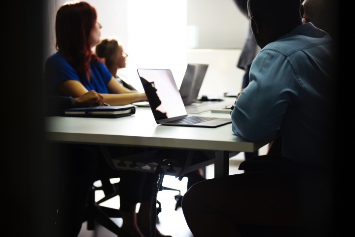 A group of people working together at a table using laptops.