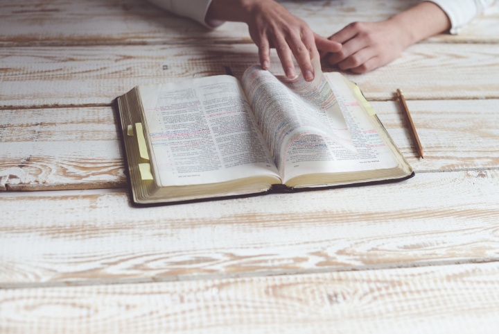 A person studying a Bible on a table.