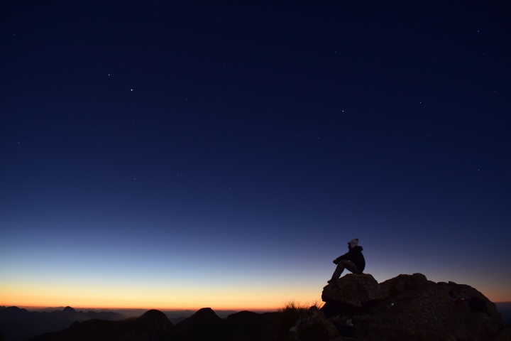 A person sitting on a rock at sunset.