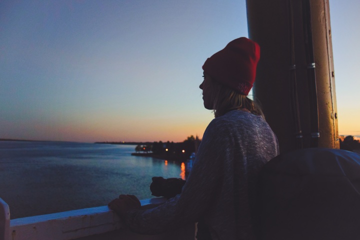 A woman looking out over a body of water at sunset.