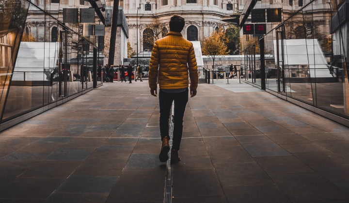 A man walking down a road in between to buildings.