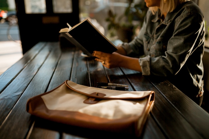 A woman reading a book at a table.