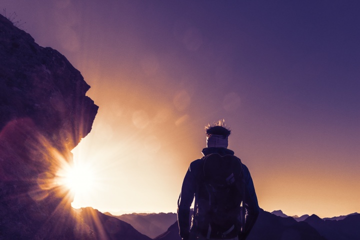 A hiker with sunrays in front of the person.