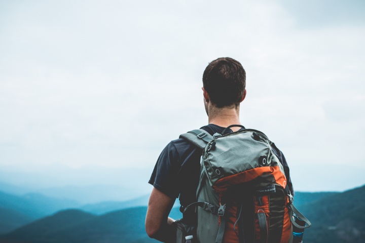 A guy wearing a backpack at the top of a hill.