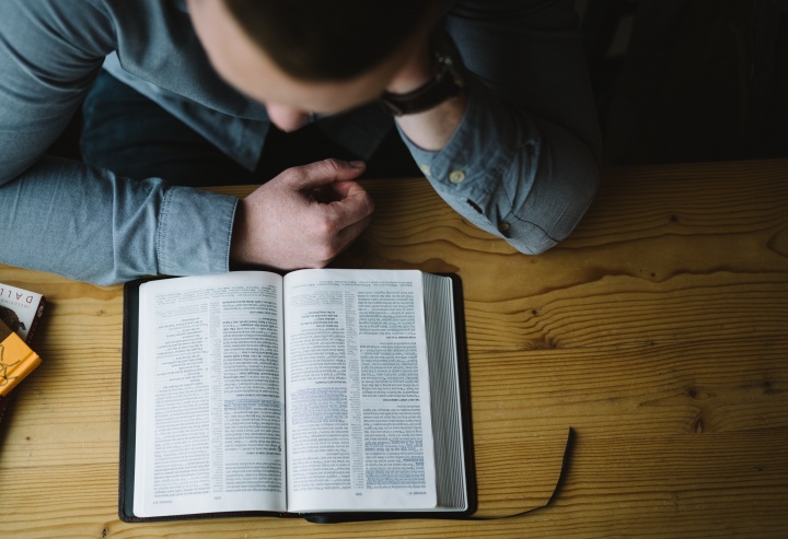 A man reading a Bible on a table.