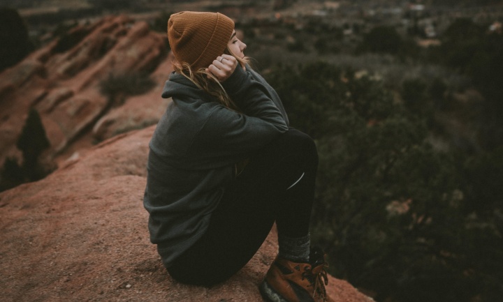 A young woman sitting on a boulder.