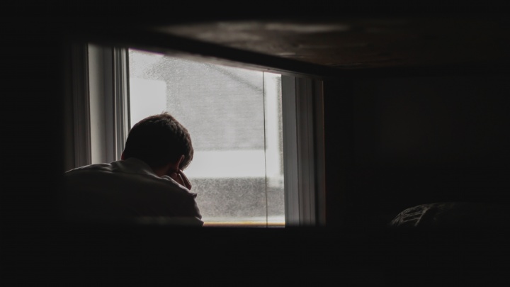 A silhouette of a man sitting by a window.