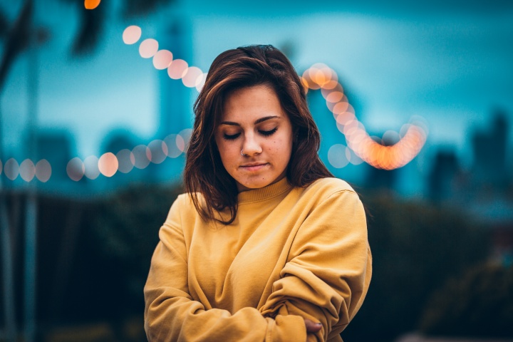 A young woman with her arms crossed and looking down.