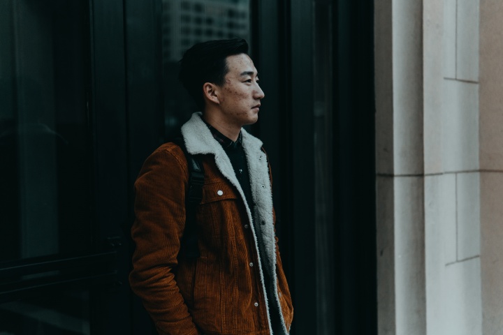 A man walking on sidewalk next to an old building.