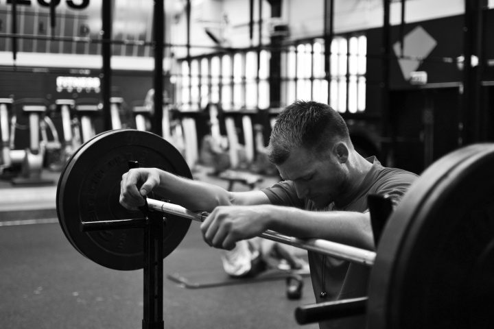 A man resting his arms on a weight lifting bar.