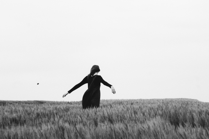 A woman with her arms open walking through a field.