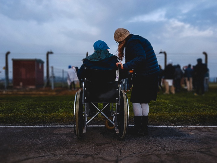 A woman helping an elderly person in a wheelchair.