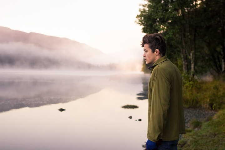 A young man looking out over a lake.