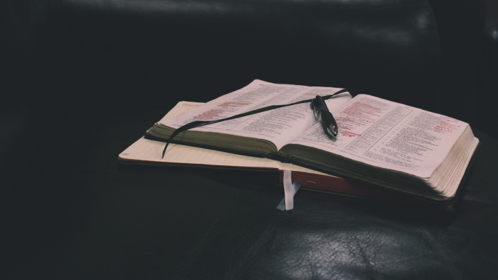 A Bible and notebook laying on a table.