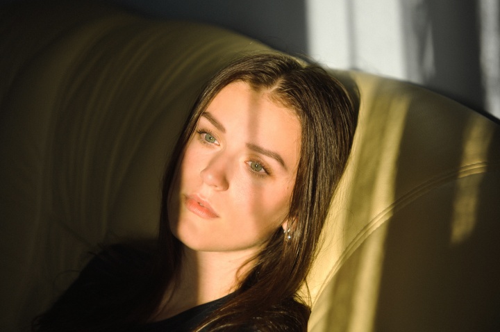 A woman sitting on a couch while her head is resting on cushion.