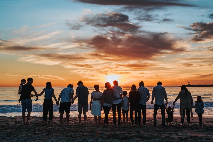 A big family gathering at the beach at sundown.