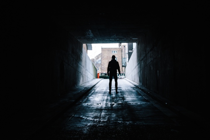 A man walking out of a dark tunnel.