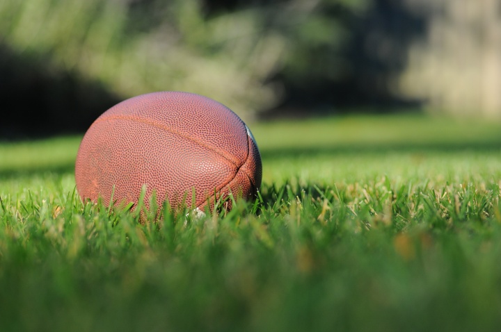 An American football on a grass field.