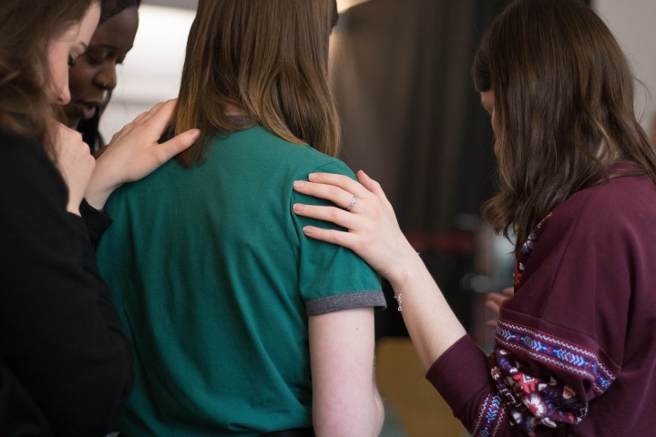 A small group of women praying together.