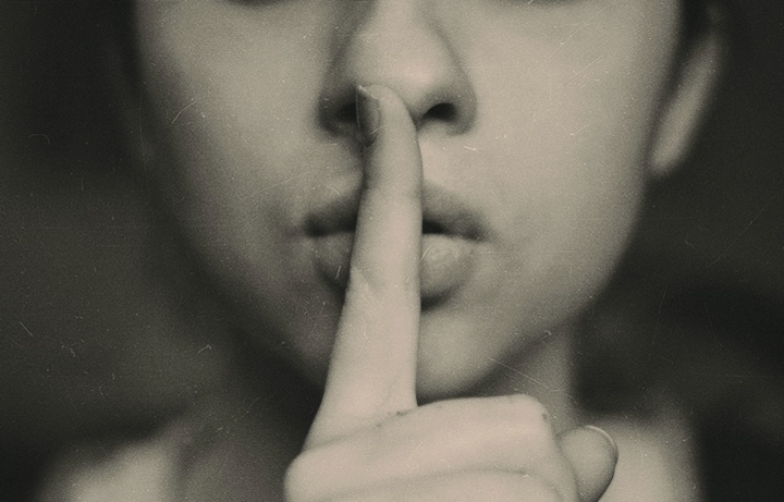 Picture of a person with finger over their lips.