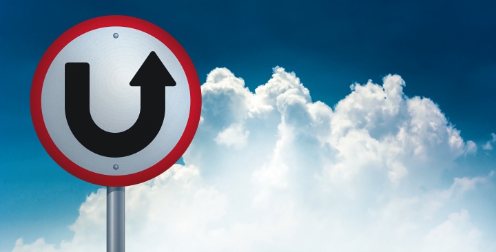 A u-turn type sign with the sky and clouds in the background.