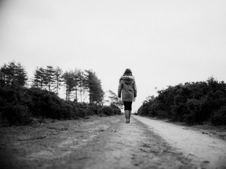 A woman walking on a dirt road.