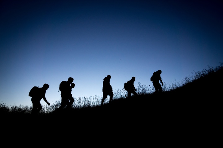 hiking people silhouetted against blue sky