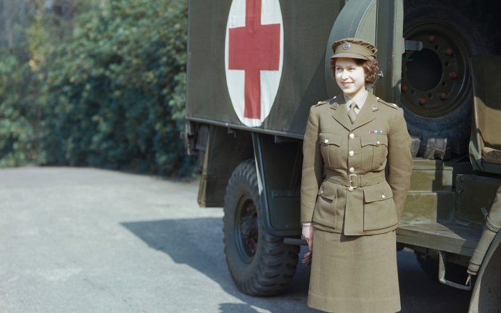 A photo of a young Queen Elizabeth standing in front of an army ambulance,