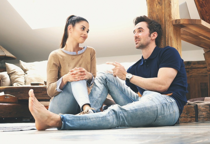 A couple sitting on the floor talking.