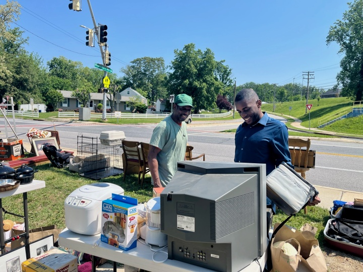 Two men examining items at a yard sale