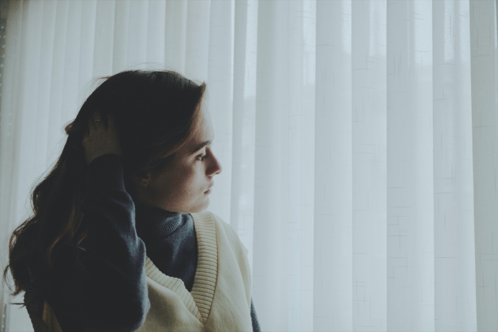 A woman looking curtains outside.