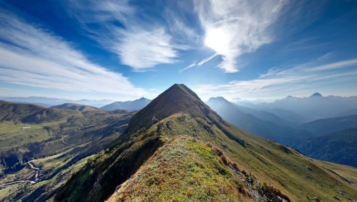 a green mountain beneath a cloudy blue sky