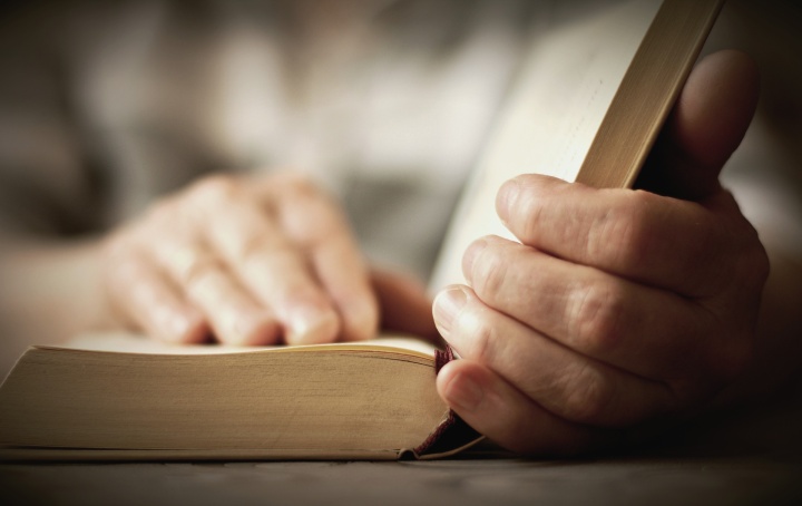 A pair of hands holding an open Bible