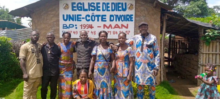 a group of people standing outside a building under a banner