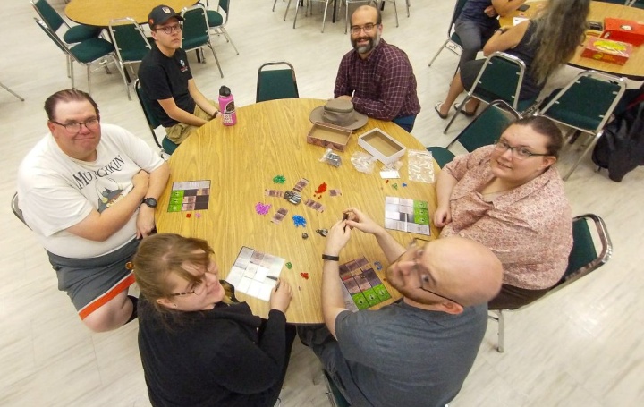 six people gathered around a table playing games