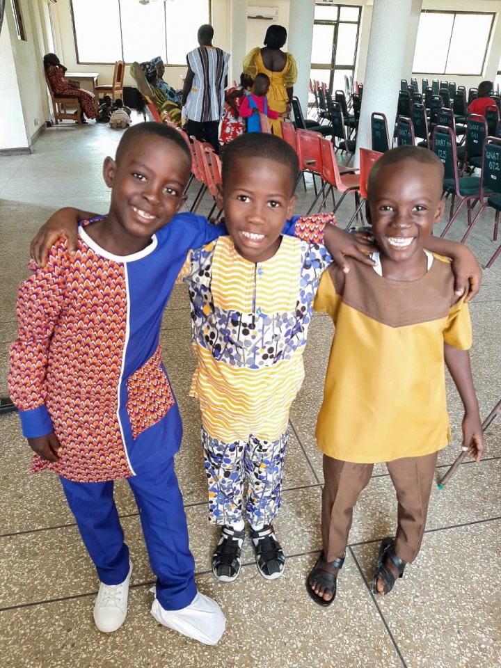 three children in traditional clothing standing arm in arm