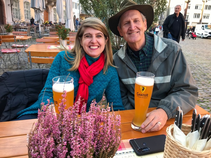 a couple seated outdoors with beers