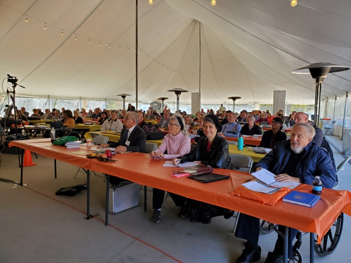 people sitting at services under a big tent