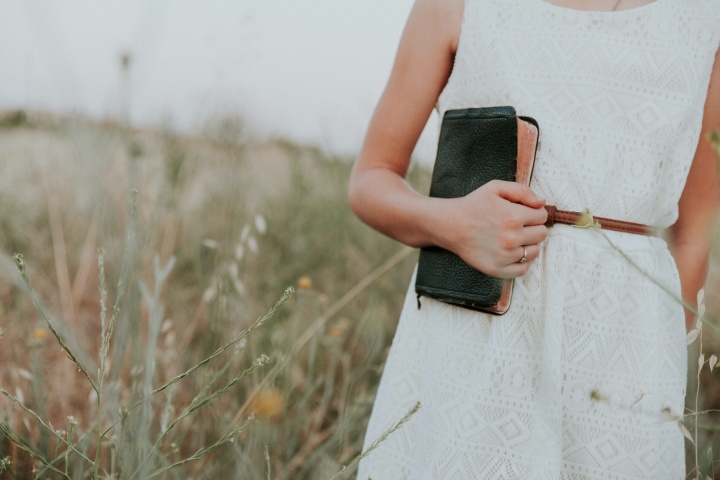 Girl holding a Bible in a field