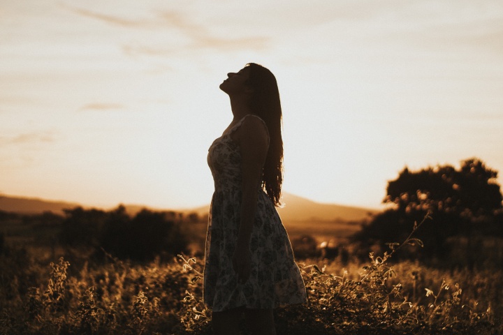 A woman standing in a field looking up.