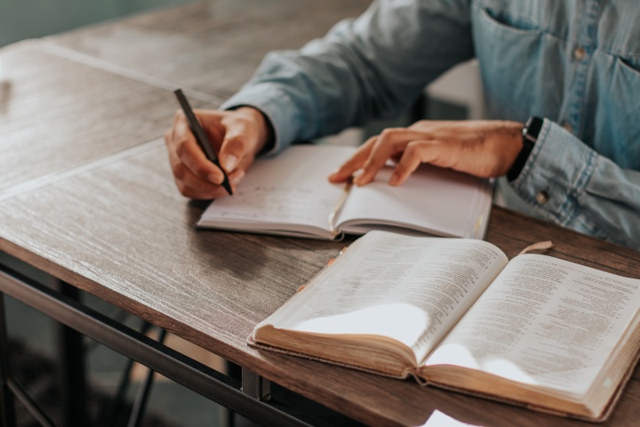 A person taking notes with a Bible open