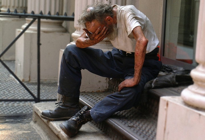 a man sitting outside with his head in his hand