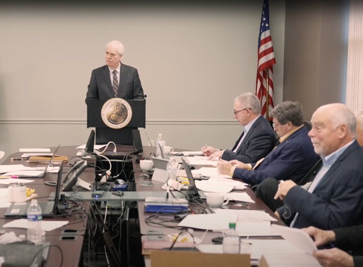 several of the council members sitting around table and listening to a speaker