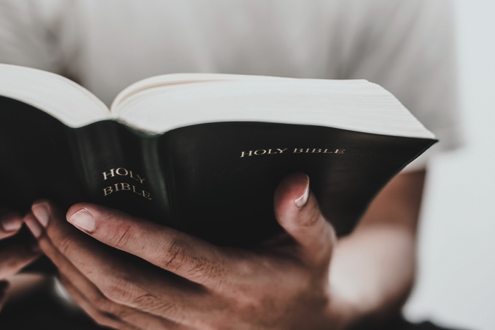 An upclose photo of a man's hands holding a Bible.