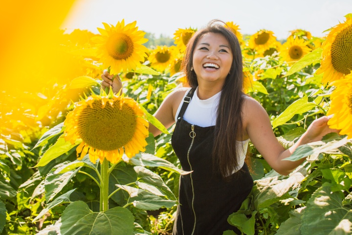 a smiling woman standing in a field of sunflowers