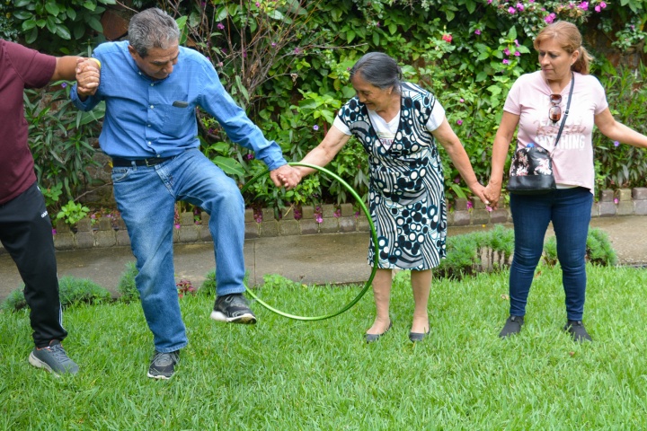 three people standing outdoors participating in a team activity with a hula hoop