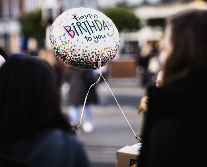 A person hold a balloon that says "Happy Birthday to you"